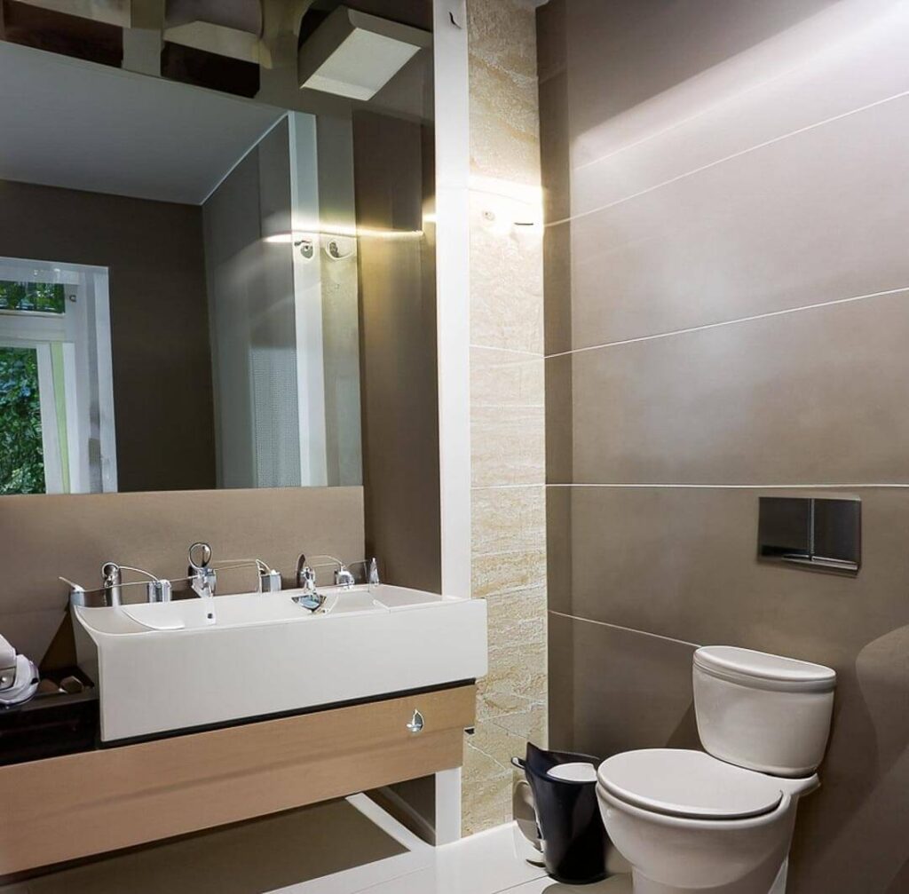 bathroom , light brown walls, a mirror and a washbasin and a trashcan