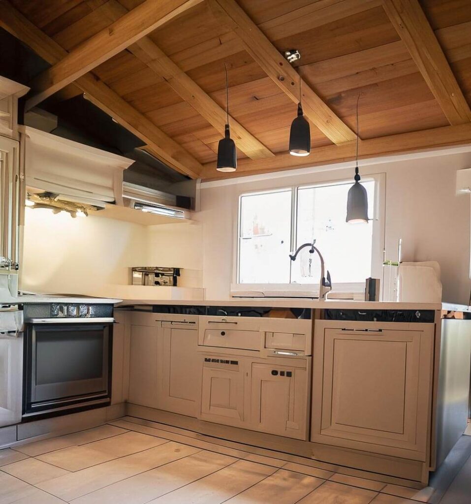 kitchen with white details , the roof is made of wood, it have 3 very little lamps