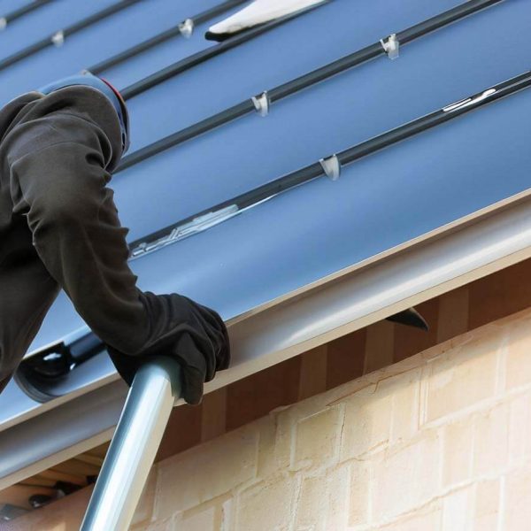 mand doing Gutters Installation with black gloves , on. a blue wall