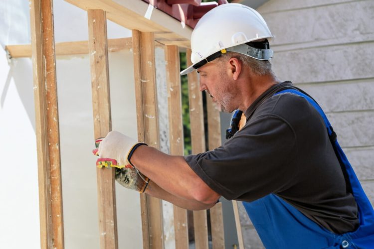 man working construction, he have a helmet , gloves and its working with wood